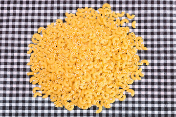 Scattered Uncooked Chifferi Rigati Pasta on Black Checkered Towel. Fat and Unhealthy Food. Classic Dry Macaroni. Italian Culture and Cuisine. Raw Pasta