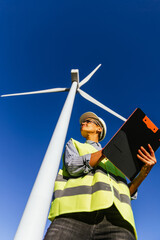 Woman skilled engineer monitors the operation of wind mills.