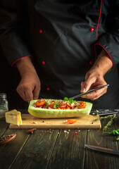 Chef in black uniform adds parsley to stuffed zucchini with meat and vegetables. The concept of cooking national stuffed zucchini or mahshi for dinner