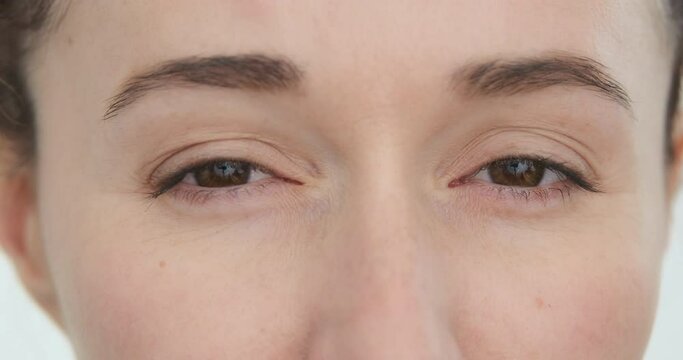 Women eyes look with distrust, close up. Suspicion in look. Female skeptic. Skeptical brown eyes looking. Person face suspicious, closeup. Adult Caucasian girl watching. Myopia disease, poor vision 