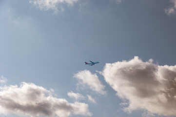 Commercial airplane between clouds. Passenger plane flies on the sky framed by cumulus clouds.