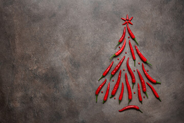 Chili pepper in the shape of a Christmas tree on a brown dark background. Abstract Christmas tree...