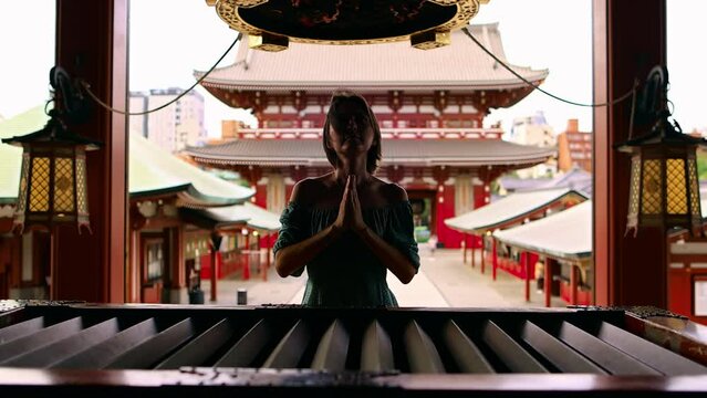 woman praying in a Buddhist shrine in Japan, Sensoji temple in Tokyo, famous Japanese buddhist temple tourism in Japan