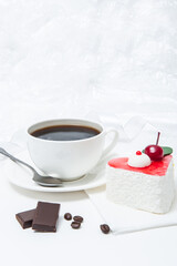 Cup of coffee with a heart-shaped cake in red icing on a plate on a table on a white background