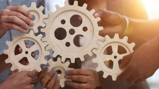 Efficient business team connects wooden gears into one