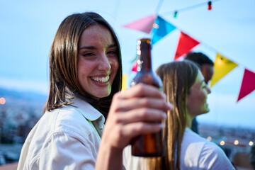 Portrait pretty young Caucasian woman toasting bottle beer in hand smiling. Attractive girl posing...