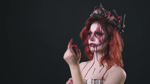 Young red hair woman with bloody queen face art, fantasy creepy look isolated on black background