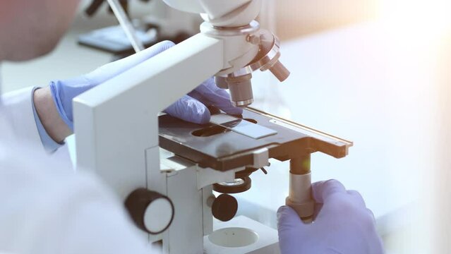 Assertive male scientist looking through a microscope