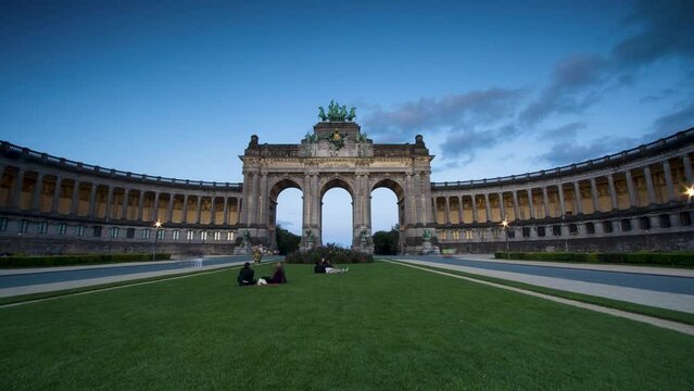 Brussels, Belgium. Parc du Cinquantenaire at sunset with the Arch built for Beglian independence in Bruxelles. Lovers and visitors having a picnic in the large park with clouds and many color people