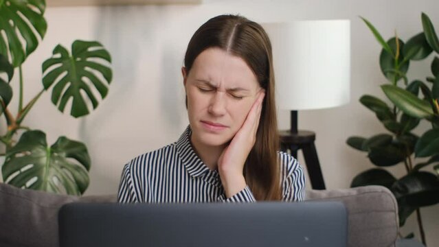 Earache, ear pain and itchy concept. Unhealthy young woman at workplace touches ear with finger experiencing pain and itchy. Stressed frowning young female plugging ear, feeling painful discomfort