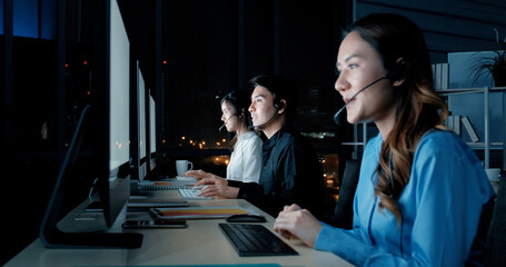 Businesswoman in headset using laptop. Side view of young serious call center operator working with...