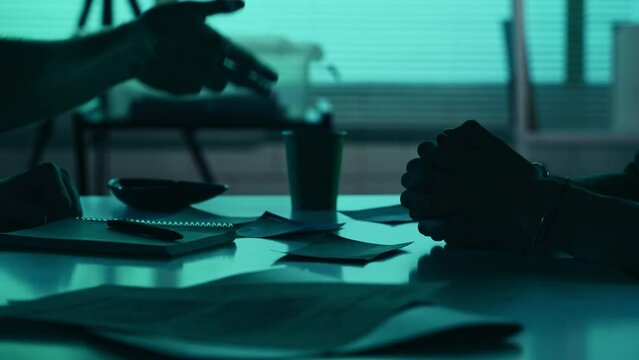 Close up detail video of the hands of a suspect, offender, perpetrator or prisoner and a detective, policeman sitting in the interrogation room, discussing the case.