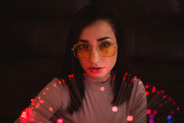 Young woman with fairy lights in darkness