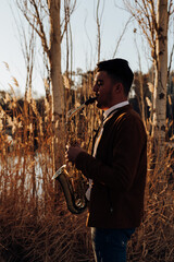young musician playing the saxophone at sunset