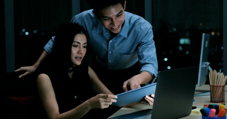 Business men and women talk and work diligently in the office at night. Not smiling even though you work hard