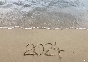 Bald kommt das neue Jahr 2024 - Frohes neues Jahr - Schrift Jahreszahl im Sand am Strand am Meer - 650262319