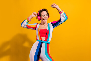 Photo of pretty carefree woman dressed striped suit dancing listening music earphones isolated yellow color background