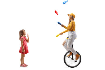 Little girl watching with amusement a woman riding a unicycle and juggling © Ljupco Smokovski