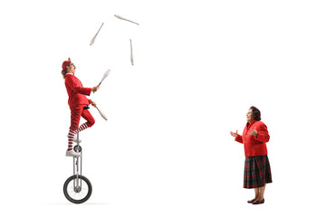 Elderly woman watching an acrobat riding a giraffe unicycle and juggling © Ljupco Smokovski