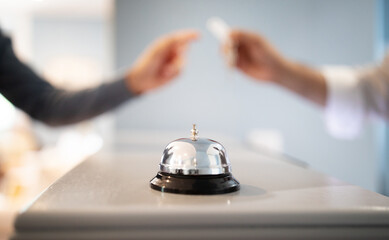 Call Bell Standing On Counter At Hotel, Receptionist Giving Key