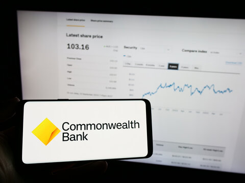Stuttgart, Germany - 09-17-2023: Person holding mobile phone with logo of company Commonwealth Bank of Australia (CBA) on screen in front of web page. Focus on phone display.