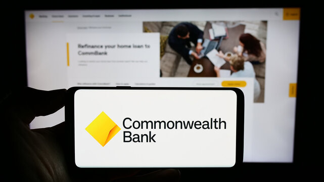 Stuttgart, Germany - 09-17-2023: Person holding smartphone with logo of company Commonwealth Bank of Australia (CBA) on screen in front of website. Focus on phone display.