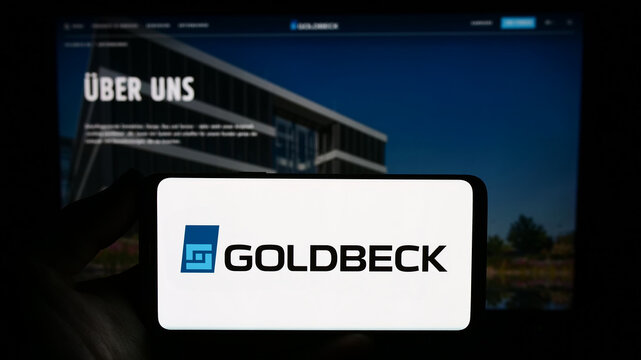 Stuttgart, Germany - 09-17-2023: Person holding smartphone with logo of German construction company Goldbeck GmbH on screen in front of website. Focus on phone display.