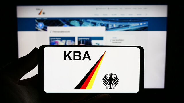 Stuttgart, Germany - 09-17-2023: Person holding smartphone with logo of German federal agency Kraftfahrt-Bundesamt (KBA) on screen in front of website. Focus on phone display.