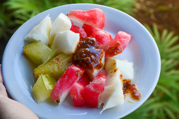 Photo of a variety of fruit "Rujak" with sauce made from brown sugar and peanuts, a fresh snack from Indonesia - Powered by Adobe
