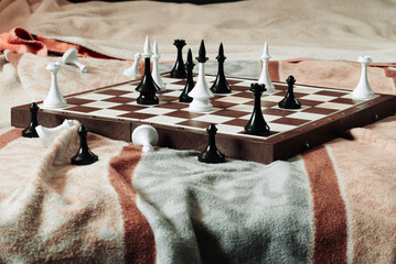 chess game, an open chessboard with chess pieces lies on a fabric in brown and blue shades, blur....