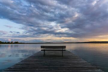 Wooden pier against the background of the lake and clouds. - obrazy, fototapety, plakaty