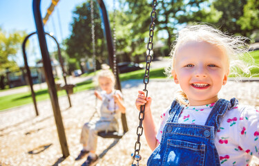 Happy 3 years old girl on a swing. Happy kid on playground