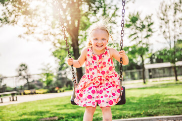 Happy 3 years old girl on a swing. Happy kid on playground