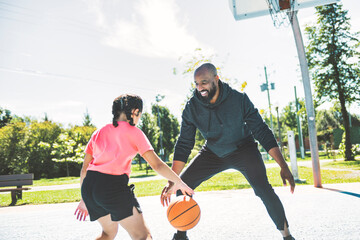 father and daughter playing basketball in the park