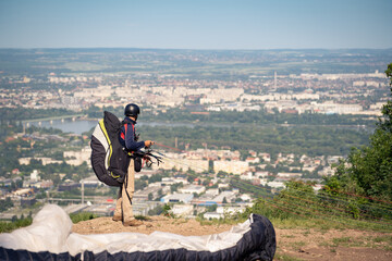 A paraglider looking at the horizon above the city, waiting for the right breeze to take off.