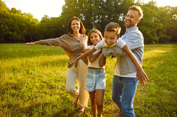 Happy family playing and having fun in nature. Parents and children playing together. Cheerful...