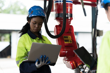 African American female engineer worker working with laptop computer for control robot arm system...