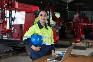 Female engineer worker working with laptop computer for maintenance robot arm system welding at...