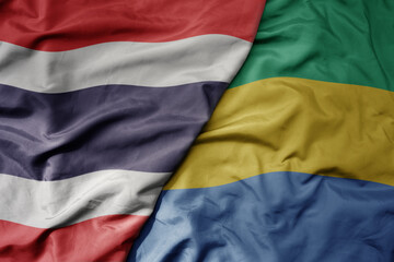big waving national colorful flag of thailand and national flag of gabon .