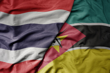 Fototapeta premium big waving national colorful flag of thailand and national flag of mozambique .