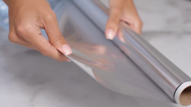 The girl holds a roll of food foil