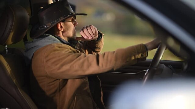 Caucasian Man Wearing Cowboy Hat Seating Behind the Pickup Truck Wheel