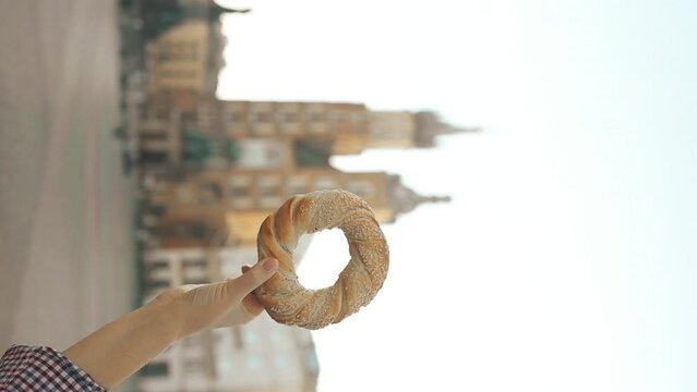 Close up of female tourist holding bagel obwarzanek traditional polish cuisine snack on the market square in Krakow in Poland. Traveling Europe. High quality FullHD footage