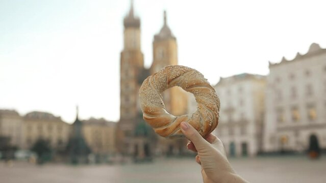 Close up of female tourist holding bagel obwarzanek traditional polish cuisine snack on the market square in Krakow in Poland. Traveling Europe. High quality FullHD footage