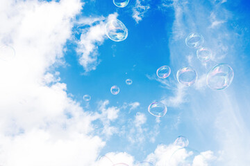 Soap bubbles against a background of blue sky with clouds