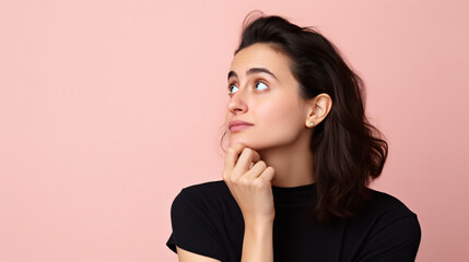 a thoughtful, creative woman gazing into the empty space, her chin resting on her arm, dressed casually against a pastel background. - obrazy, fototapety, plakaty