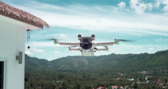 Modern drone quadcopter flying in air in slow motion for filming travel blogger content during summer holidays. Concept of making aerial view content while summer traveling at tropical paradise