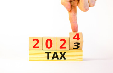 2024 tax new year symbol. Businessman turns a wooden cube and changes words Tax 2023 to Tax 2024....