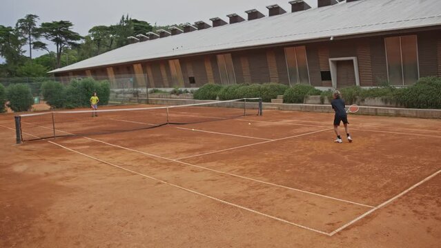  Two Young Guys Play Tennis Outdoors