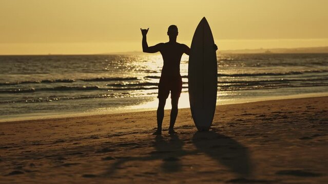 Surfer with surfboard at early sunset